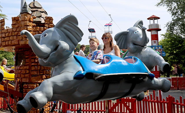 Lady and young boy on flying elephant amusement ride