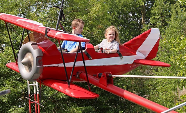 Young boy and young girl on aeroplane theme park ride