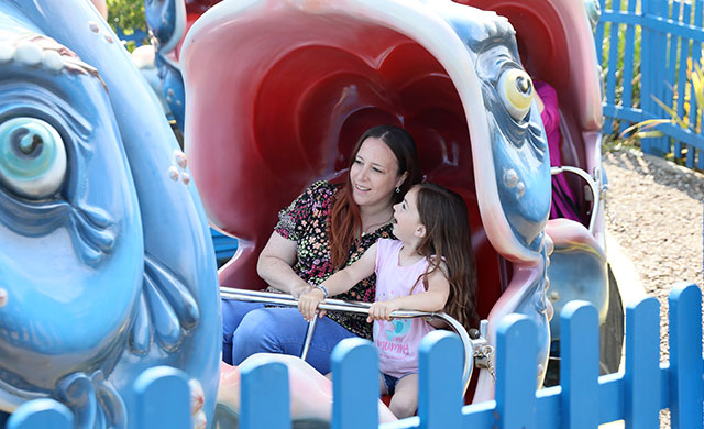 Woman and young girl on whale theme park ride
