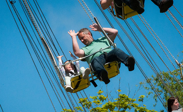 Man and young girl on swings at a theme park