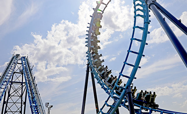 blue rollercoaster with sunny sky going through a loop